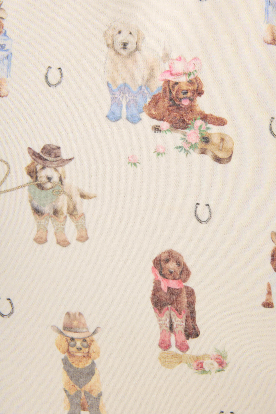 The DOGS PJ SET RUFF ON THE RANGE by P.J. Salvage features a playful print of dogs in Western outfits with cowboy hats and boots, surrounded by horseshoes and flowers on a light background.