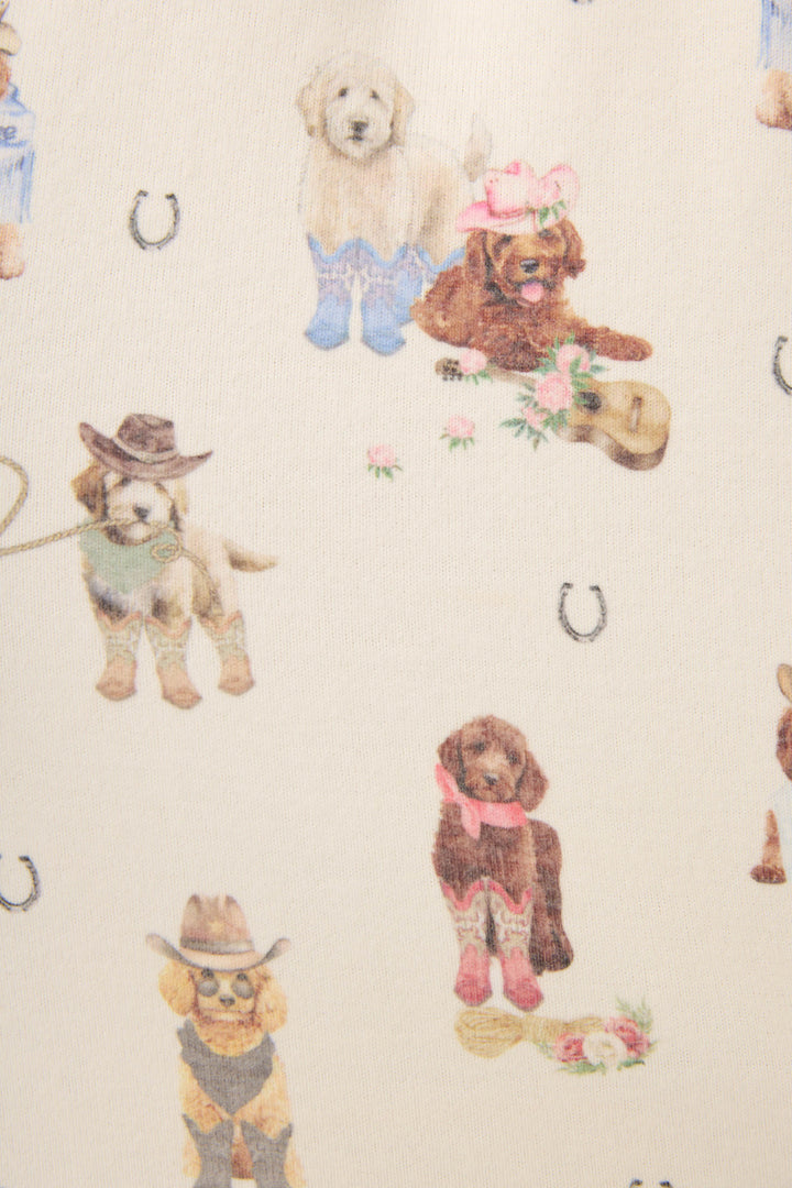 The DOGS PJ SET RUFF ON THE RANGE by P.J. Salvage features a playful print of dogs in Western outfits with cowboy hats and boots, surrounded by horseshoes and flowers on a light background.