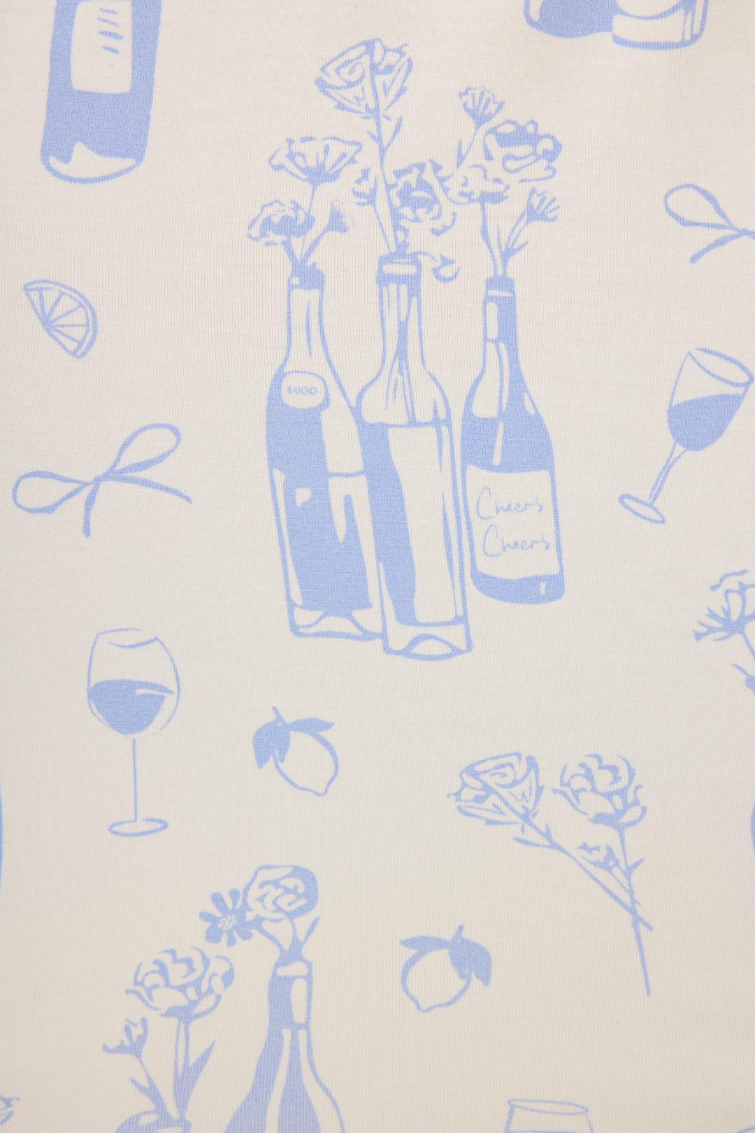 The Parisian Dreams Whimsical Print Open Leg Pant by P.J. Salvage features blue line drawings of wine bottles, flowers, glasses, lemons, and bows on a light background—one bottle’s label reads Cheers Cheers.