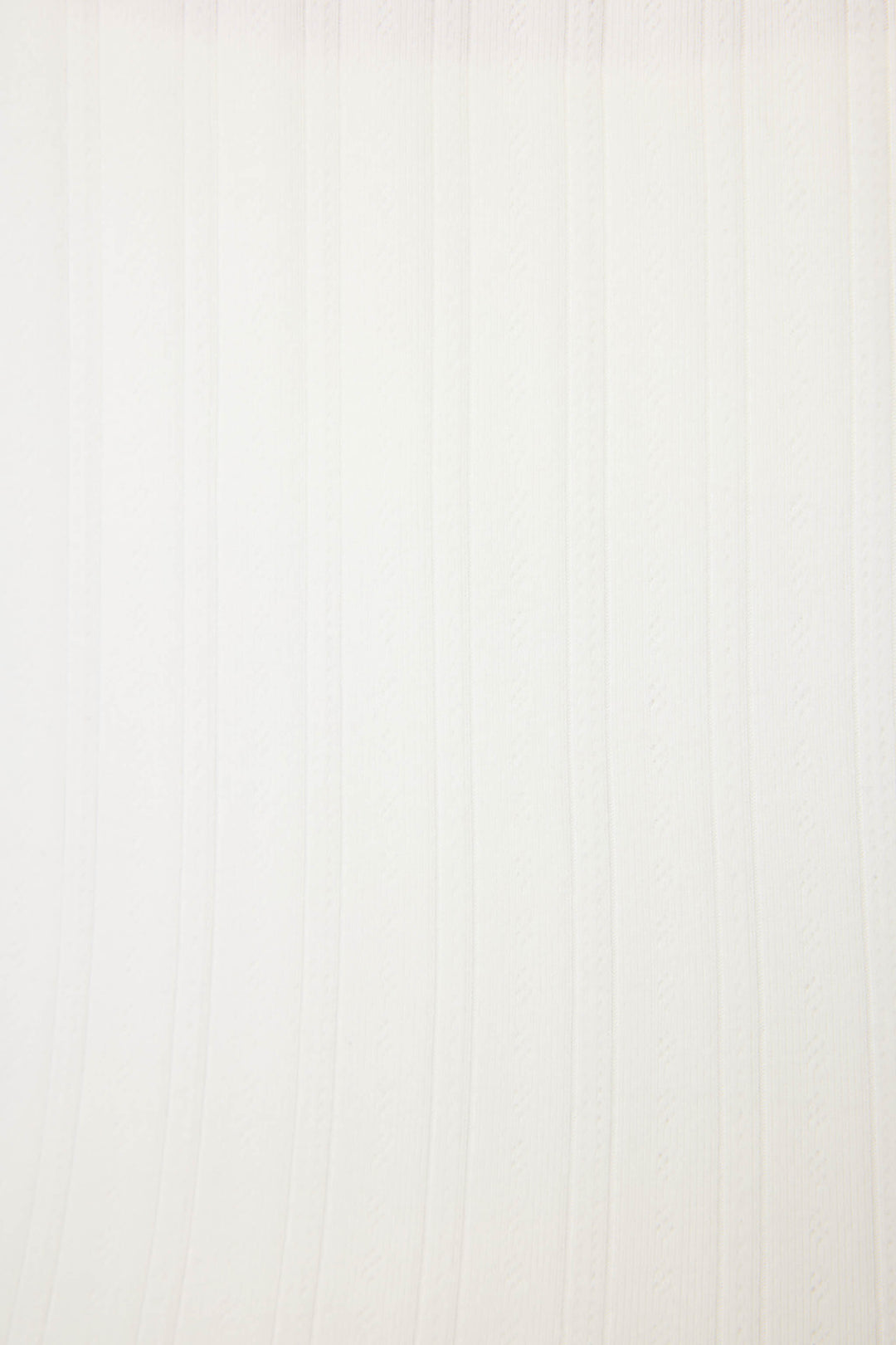The Pointelle Essentials Solid Ivory Cardigan by P.J. Salvage features a white textured surface with vertical, slightly wavy lines and subtle embossed patterns evenly spaced across the background.