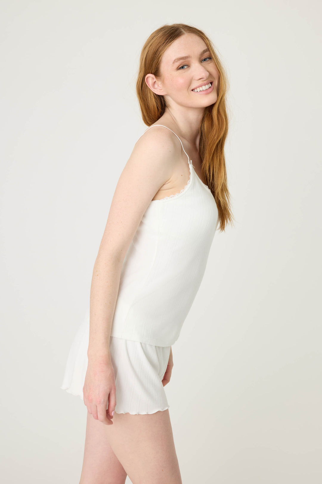 A woman with long red hair models the P.J. Salvage Pointelle Essentials Solid Ivory Camisole, smiling and slightly leaning forward against a plain light background.