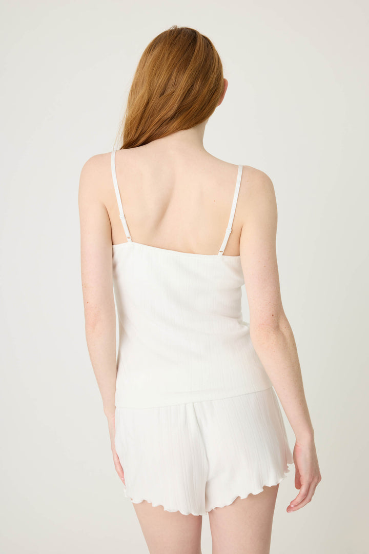 A person with long, light brown hair is seen from behind wearing the P.J. Salvage Pointelle Essentials Solid Ivory Camisole and matching white shorts against a plain, light background.
