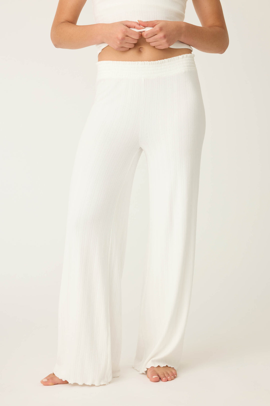 A person stands barefoot in P.J. Salvage’s Pointelle Essentials Solid Ivory Open Leg Pant, featuring a high elastic waistband and loose, wide-leg fit. The cropped photo shows only the pants against a plain light background.
