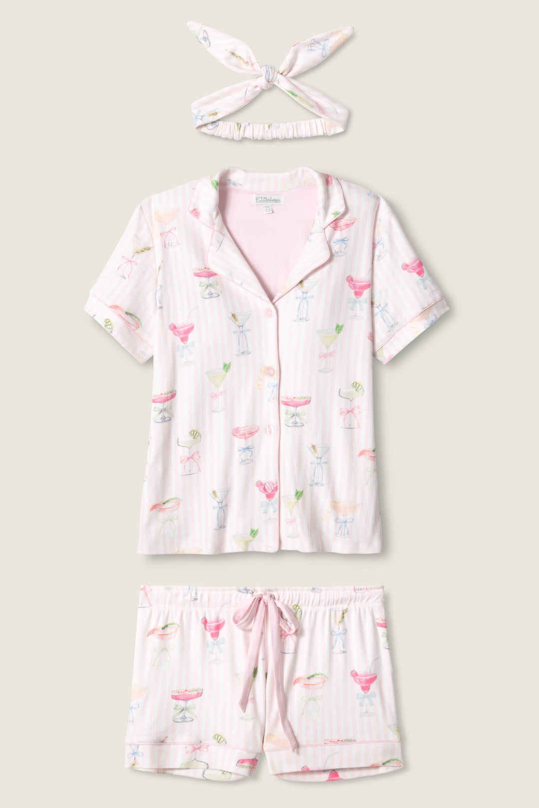 The P.J. Salvage Pretty Punch Cocktail Print 3-Piece Short Set features a short-sleeve button-up top, drawstring shorts, and a matching headband in light pink with colorful cocktail-themed prints.