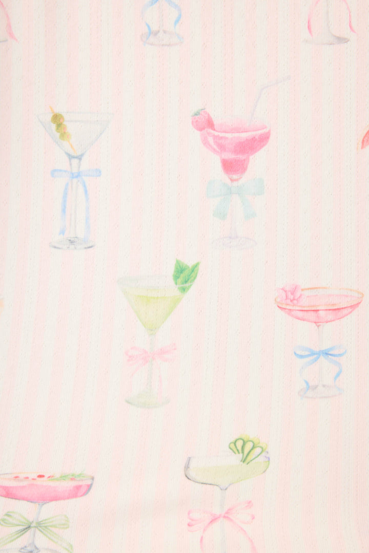 The Pretty Punch Cocktail Print 3-Piece Short Set by P.J. Salvage features light pink fabric with subtle stripes and pastel cocktail glass illustrations, each uniquely garnished and accented with small ribbons at the base.