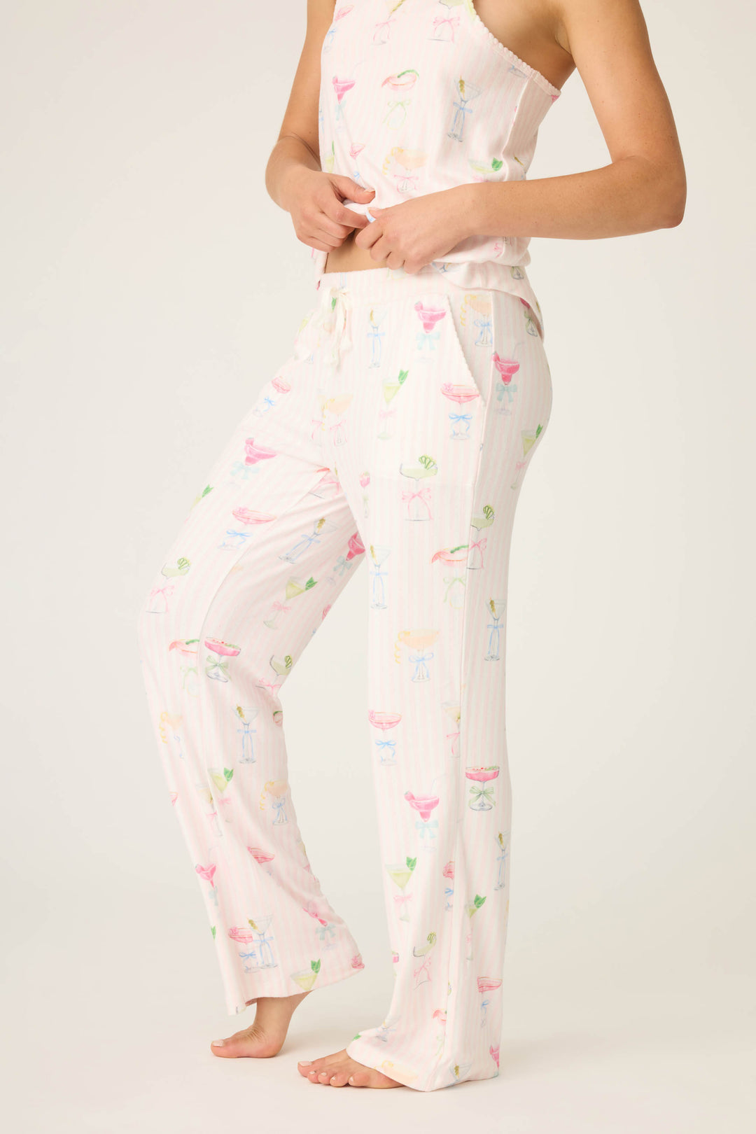 A person models the Pretty Punch Cocktail Print Open Leg Pants by P.J. Salvage—loose-fitting pajama pants with a pastel cocktail print—paired with a matching sleeveless top, barefoot against a plain background.