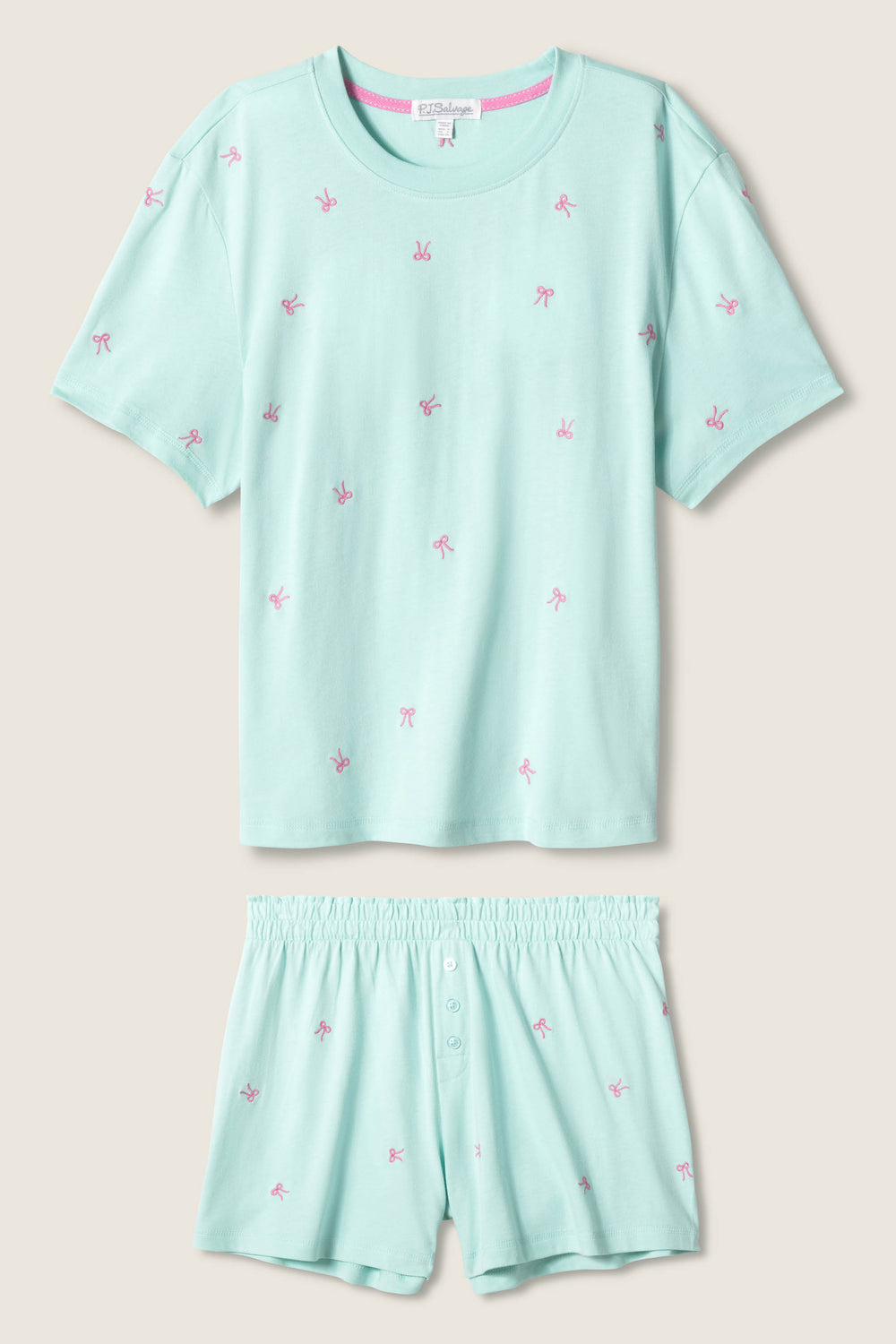 The Pretty Punch Bow Print Loungewear Short Set by P.J. Salvage features a light blue short-sleeve T-shirt and matching shorts with pink bow prints, an elastic waistband, and button detail for comfort and style.