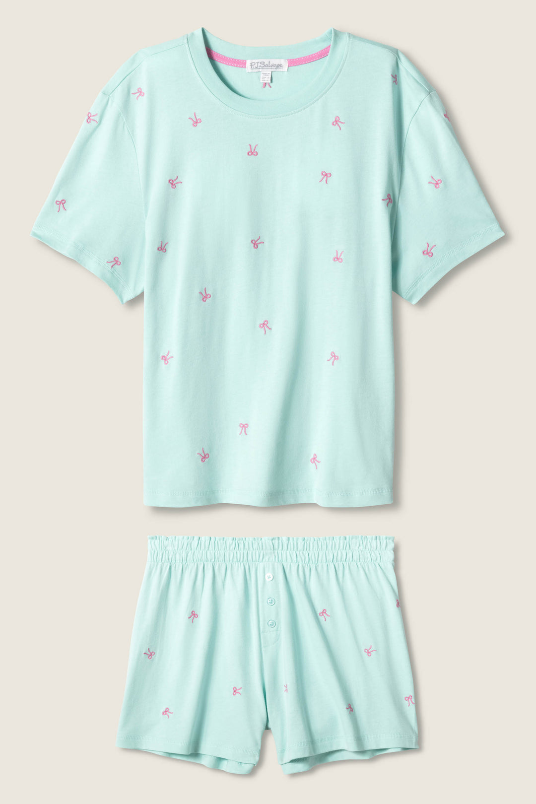 The Pretty Punch Bow Print Loungewear Short Set by P.J. Salvage features a light blue short-sleeve T-shirt and matching shorts with pink bow prints, an elastic waistband, and button detail for comfort and style.