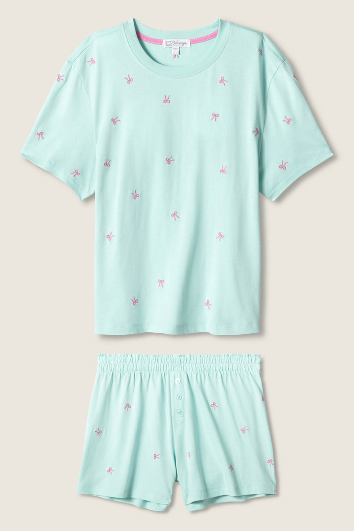 The Pretty Punch Bow Print Loungewear Short Set by P.J. Salvage features a light blue short-sleeve T-shirt and matching shorts with pink bow prints, an elastic waistband, and button detail for comfort and style.