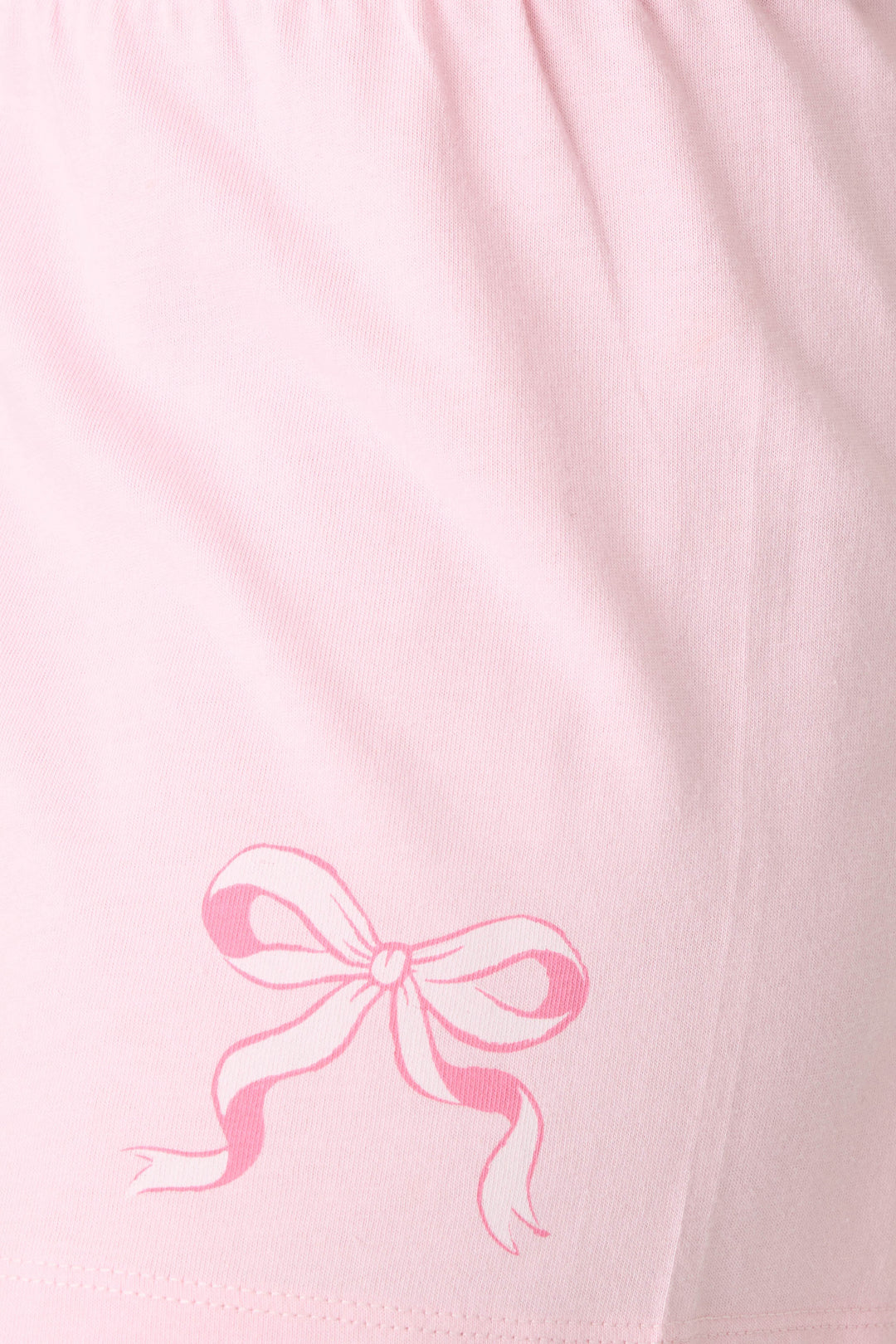 Close-up of the Pretty Punch Thats The Spirit Loungewear Short Set by P.J. Salvage, featuring light pink fabric with a darker pink printed ribbon bow near the hem and gathered detailing at the top, ideal for comfortable lounging.