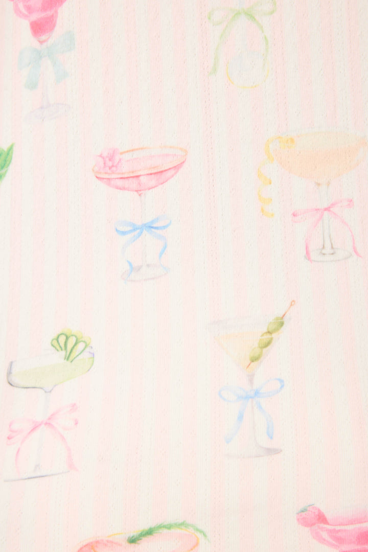 The Pretty Punch Cocktail Print PJ Set by P.J. Salvage features a playful pattern of pastel cocktail glasses with bows and fruit garnishes on a pink striped background.