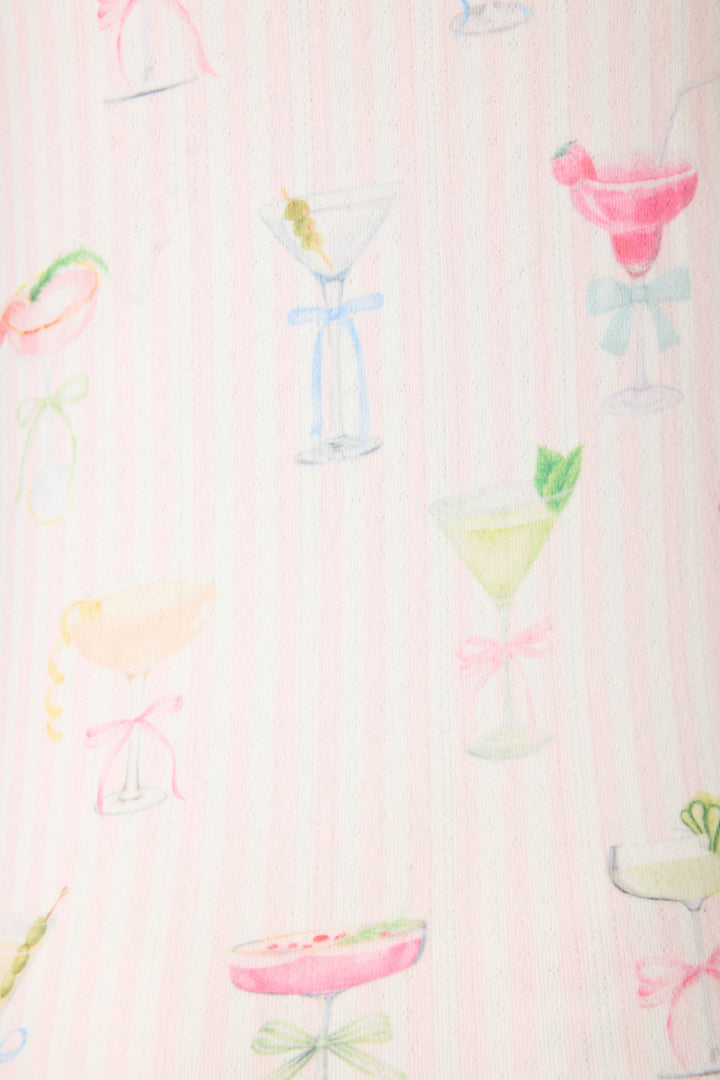A close-up of the Pretty Punch Cocktail Print Racerback Tank Top by P.J. Salvage, featuring pastel cocktail glasses with fruit and ribbons on a pale pink and white striped fabric.