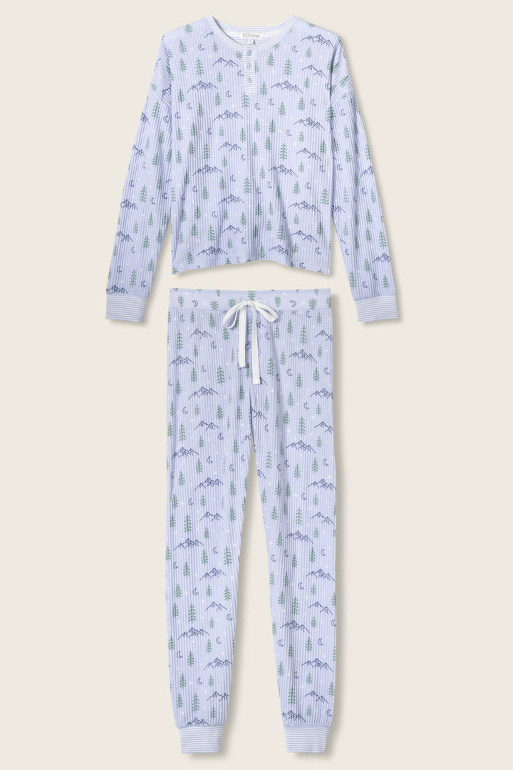The P.J. Salvage Ski Jammie Classics Winter Tree Print PJ Set features a light blue, tree and blue animal patterned two-piece with a long-sleeve button-up top and drawstring pants, displayed flat on a neutral background.