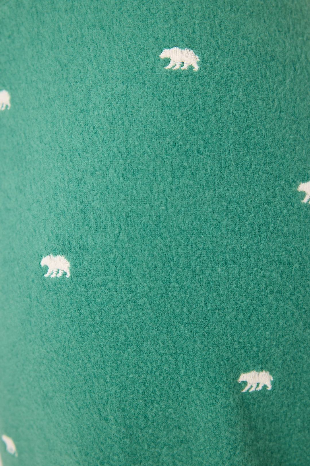Close-up of the P.J. Salvage The Outsider Embroidered Bear Fleece Banded Pants, showing green fabric with evenly spaced, small white embroidered bear silhouettes.