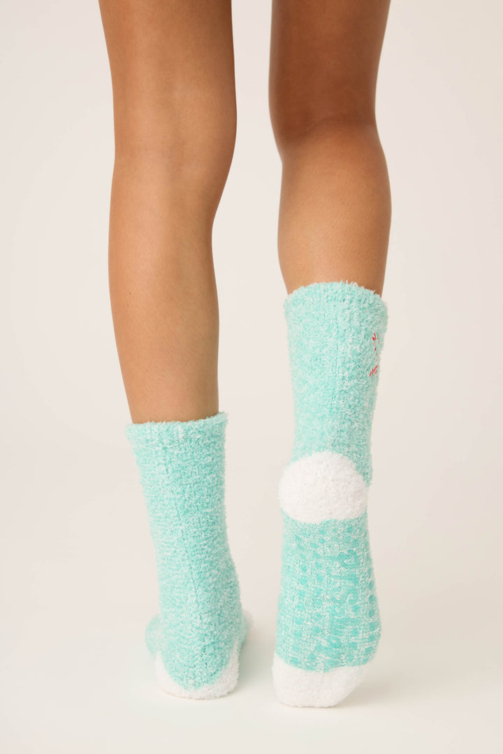 A person is shown from the knees down on a light background, wearing P.J. Salvage Candy Cane Fuzzy Crew Socks in mint green with white cushioned heels and toes.