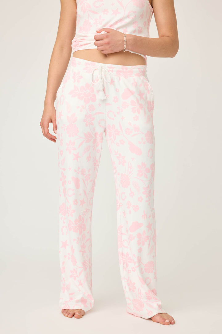 A person wearing P.J. Salvage Wild Flower Western Floral Print Open Leg Pants stands barefoot against a plain light background. The pants feature a light pink and white floral pattern with a drawstring waist; face is not visible.