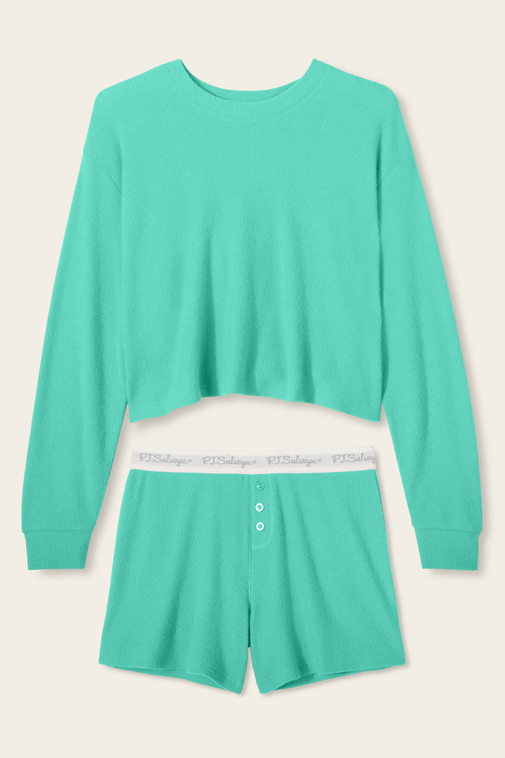 The Boyfriend Boxer Solid Green Short Set by P.J. Salvage features a ribbed, soft material with a long-sleeve cropped top and high-waisted shorts, accented by white buttons and an elastic waistband with repeated text.