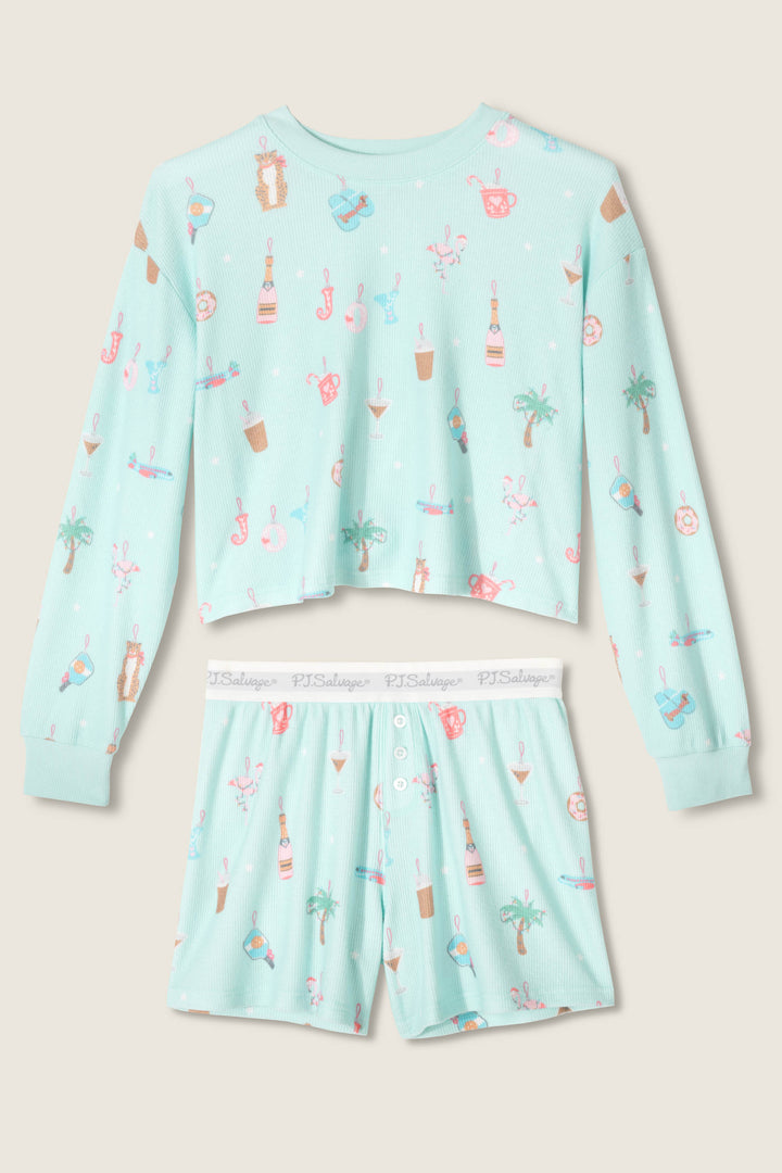 The P.J. Salvage Boyfriend Boxer Ornament Print Shorts Set includes a long-sleeve, light blue crop top and shorts with a tropical beach-themed print featuring palm trees, drinks, sunglasses, and seashells.