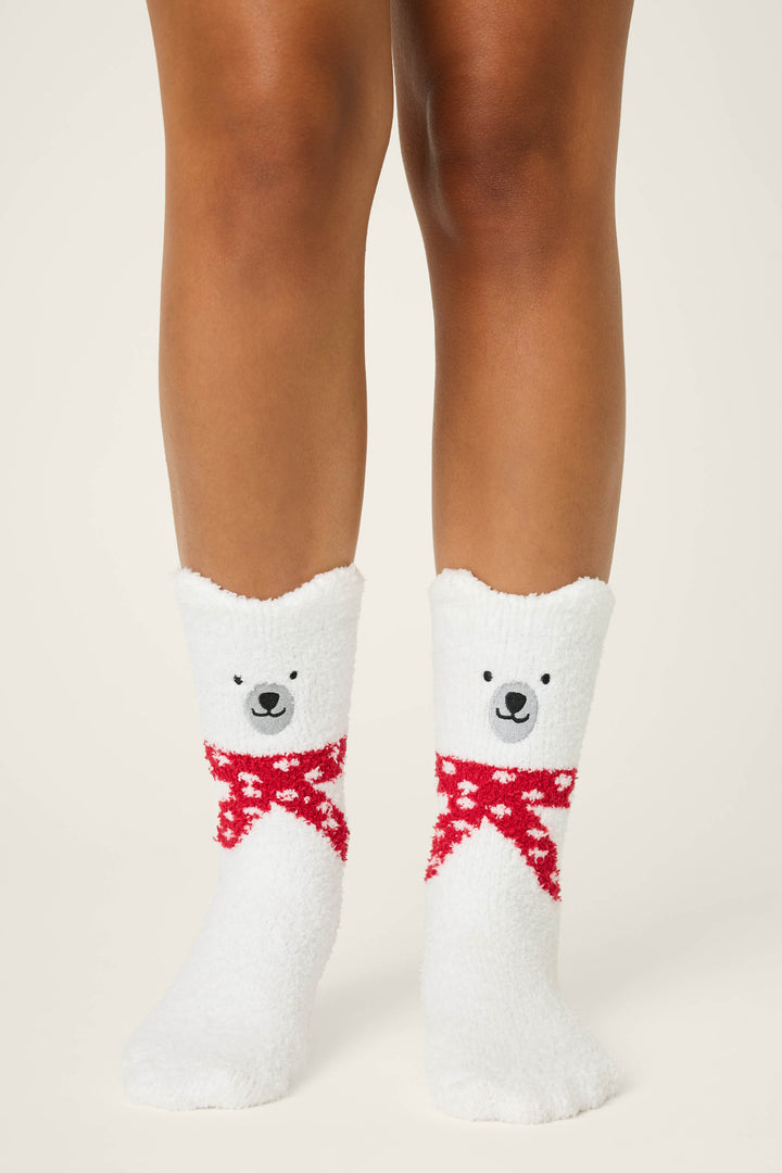 A person wearing P.J. Salvage BEAR SOCKS FAM JAM BEARLY AWAKE—fuzzy white mid-calf socks with a bear face and red scarf—stands on a neutral background, showing their lower legs.