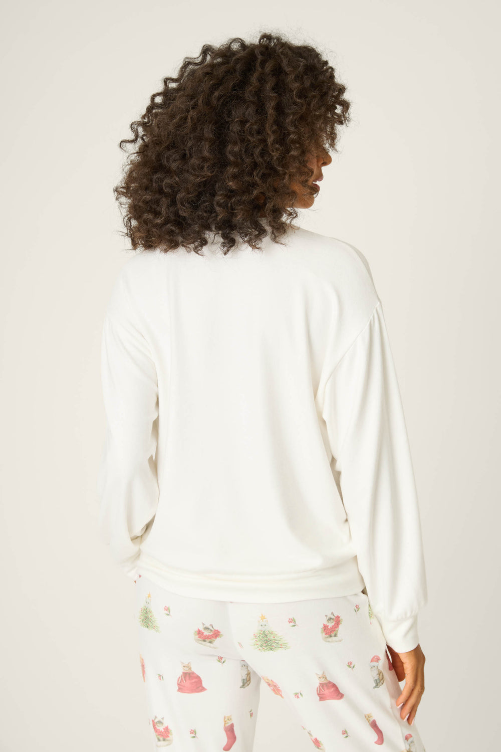 A person with curly hair is shown from the back, wearing the P.J. Salvage Feline Festive Cat Print Sweater featuring a playful holiday cat print.