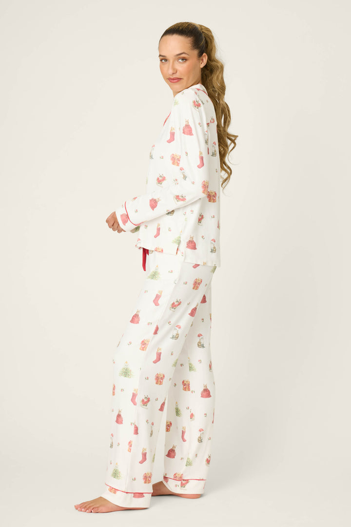 A woman with long hair stands barefoot, wearing the P.J. Salvage Feline Festive Cat Print PJ Set. She faces sideways, looking at the camera, against a plain off-white background.