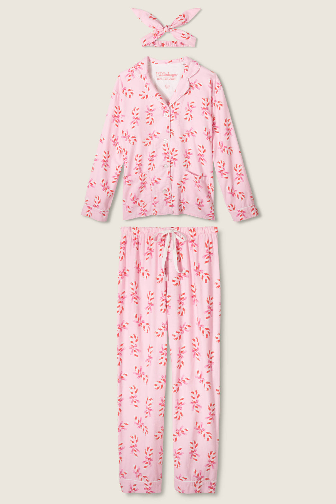 The P.J. Salvage 3-Piece Candy Cane Print Plus Size Flannel PJ Set includes a long-sleeve button-up top, matching pants, and a headband—all in light pink flannel with red and white candy cane print.