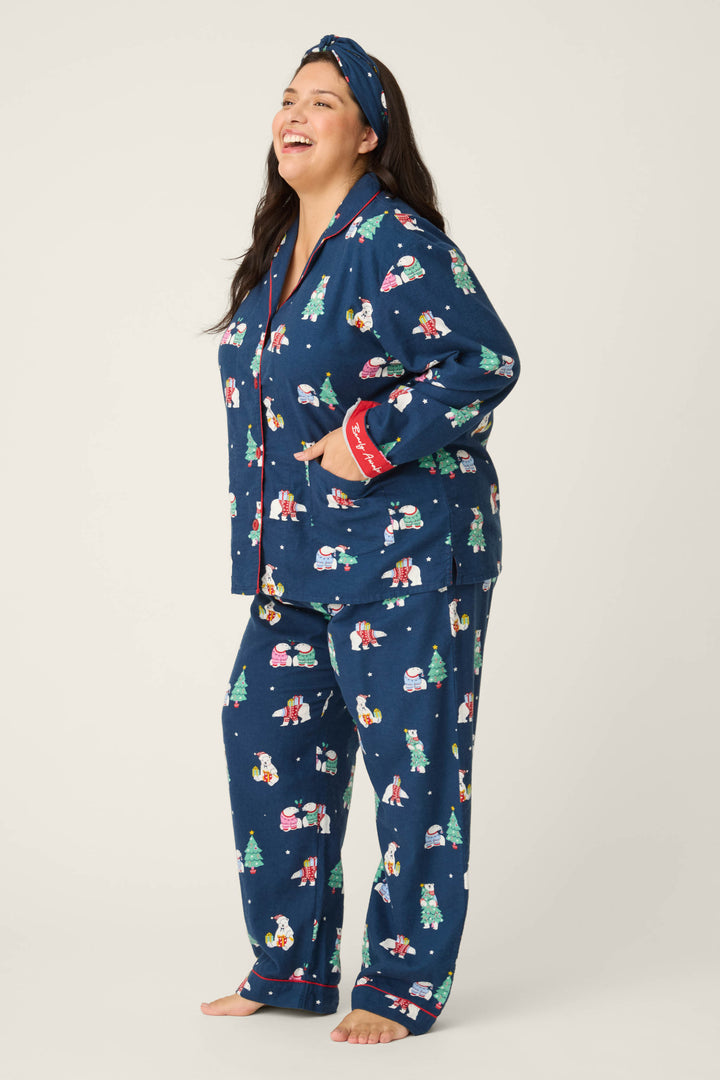 A woman smiles barefoot on a light background, wearing the P.J. Salvage 3-Piece Bear Print Plus Size Flannel PJ Set, featuring matching holiday-themed prints and a coordinating headband.