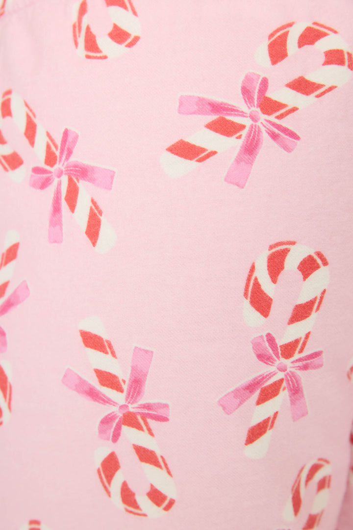 A close-up of P.J. Salvage’s Sweeter Than Sugar Candy Cane Print Flannel Shorts shows pink cotton flannel covered in red and white candy canes with pink ribbon bows—festive, cozy holiday pajama shorts.