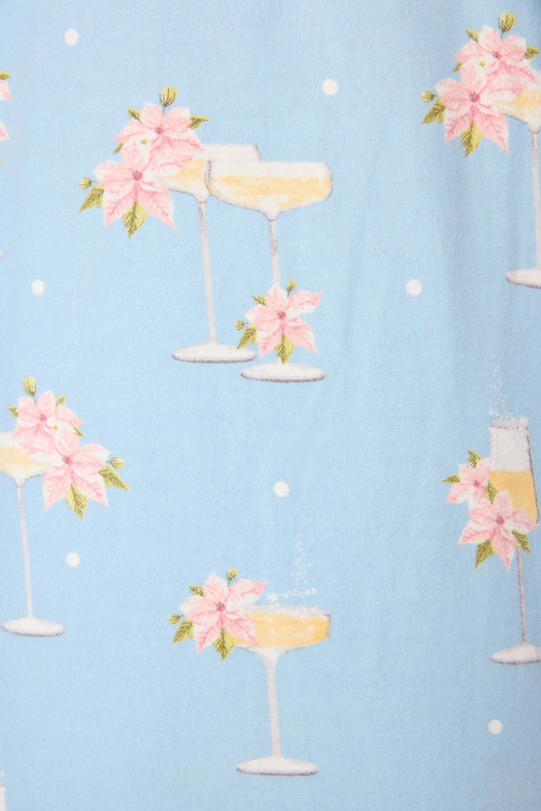 The Fizz The Season 3-Piece Flannel PJ Set by P.J. Salvage features light blue fabric with white polka dots and prints of champagne coupe and flute glasses adorned with pink poinsettias and green leaves.