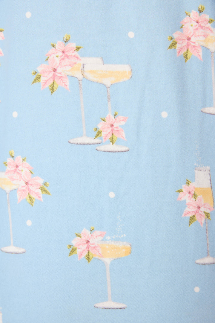 The Fizz The Season 3-Piece Flannel PJ Set by P.J. Salvage features light blue fabric with white polka dots and prints of champagne coupe and flute glasses adorned with pink poinsettias and green leaves.