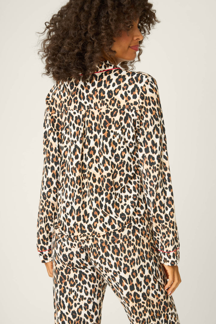 A person with curly hair is seen from behind wearing the P.J. Salvage Holiday Dreams Leopard Print Long Sleeve Top, paired with matching pants, against a plain light background.
