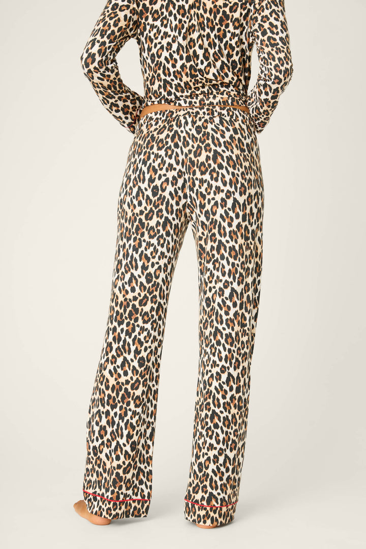 A person stands barefoot with their back to the camera, wearing P.J. Salvage Holiday Dreams Leopard Print Open Leg Pants against a plain light background.