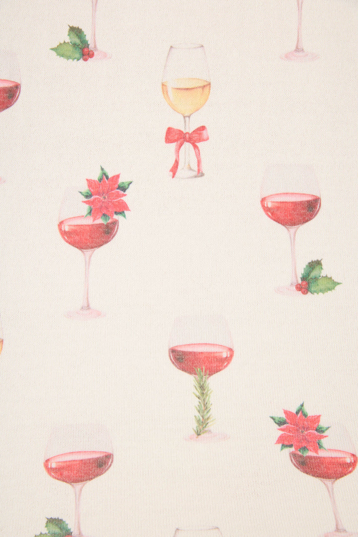 The P.J. Salvage Let's Get Toasty Holiday Wine Print Plus Size Pants Set features a cream background with wine glasses filled with red and white wine, adorned with holly, poinsettias, ribbons, and rosemary sprigs.