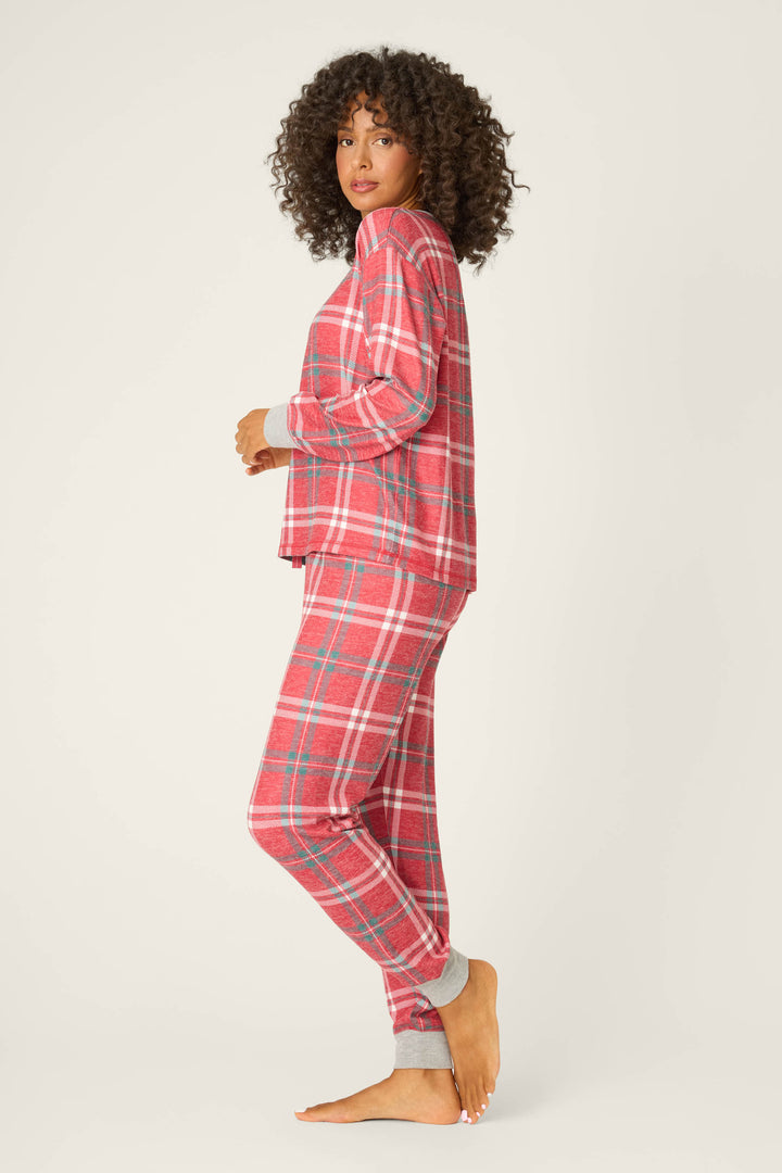 A person stands barefoot in profile on a light background, wearing the P.J. Salvage Let's Get Toasty Red Plaid Pants Set with gray cuffs.