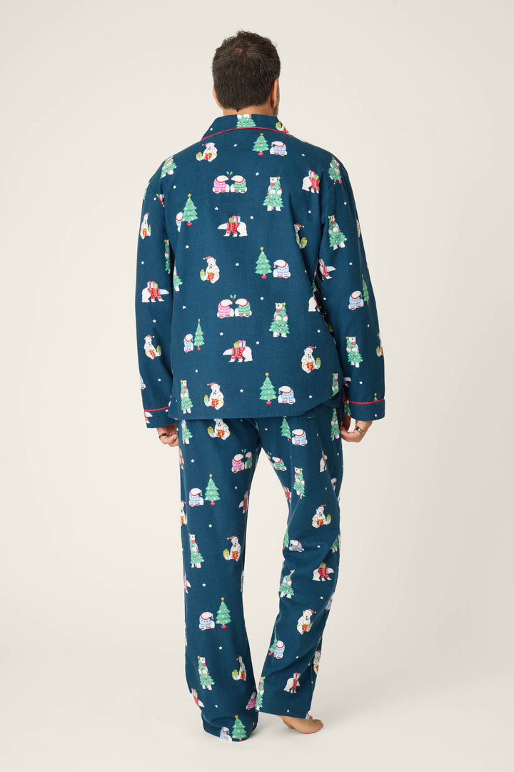 A person stands barefoot facing away in the BEARS MENS PJ SET FAM JAM BEARLY AWAKE by P.J. Salvage, featuring blue pajamas with festive bear prints, against a plain light background.