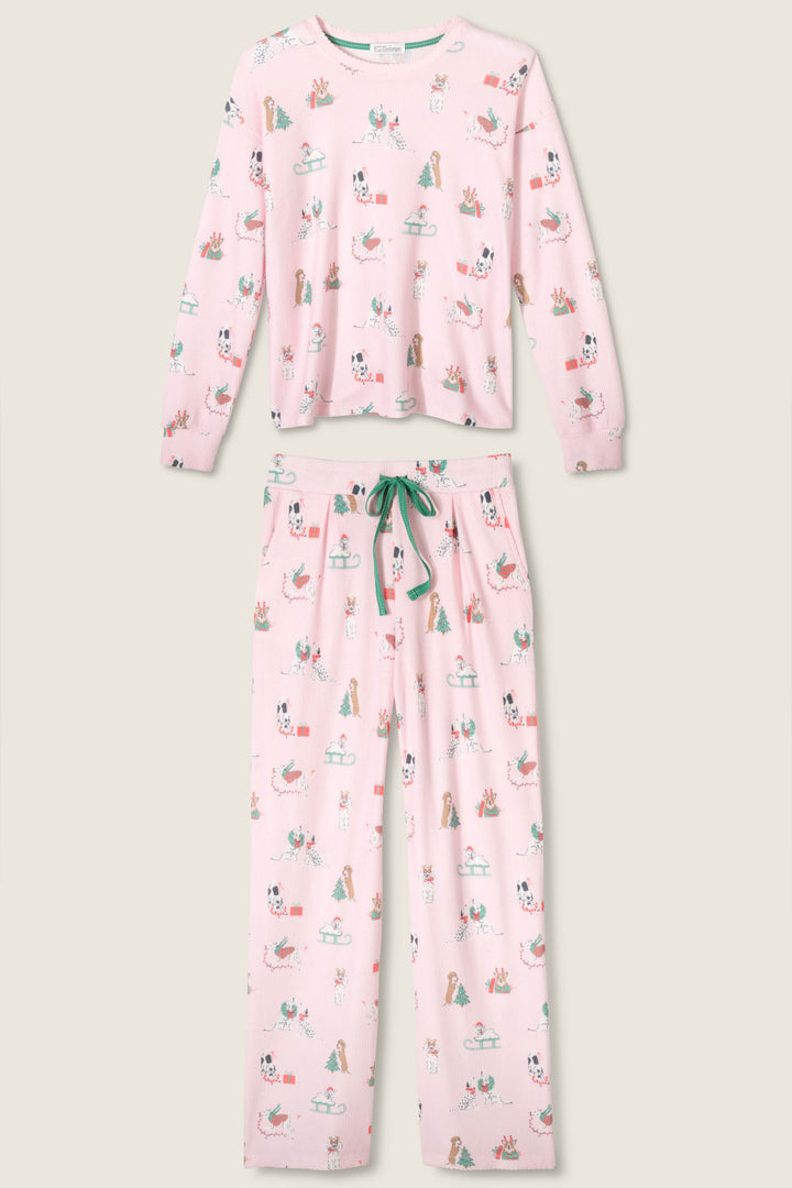 The Peace & Pawlidays Dog Print Pants Set by P.J. Salvage is a pink pajama set with a long-sleeve top and pants, both featuring colorful dog, bone, and tennis ball prints, plus a green drawstring waist.
