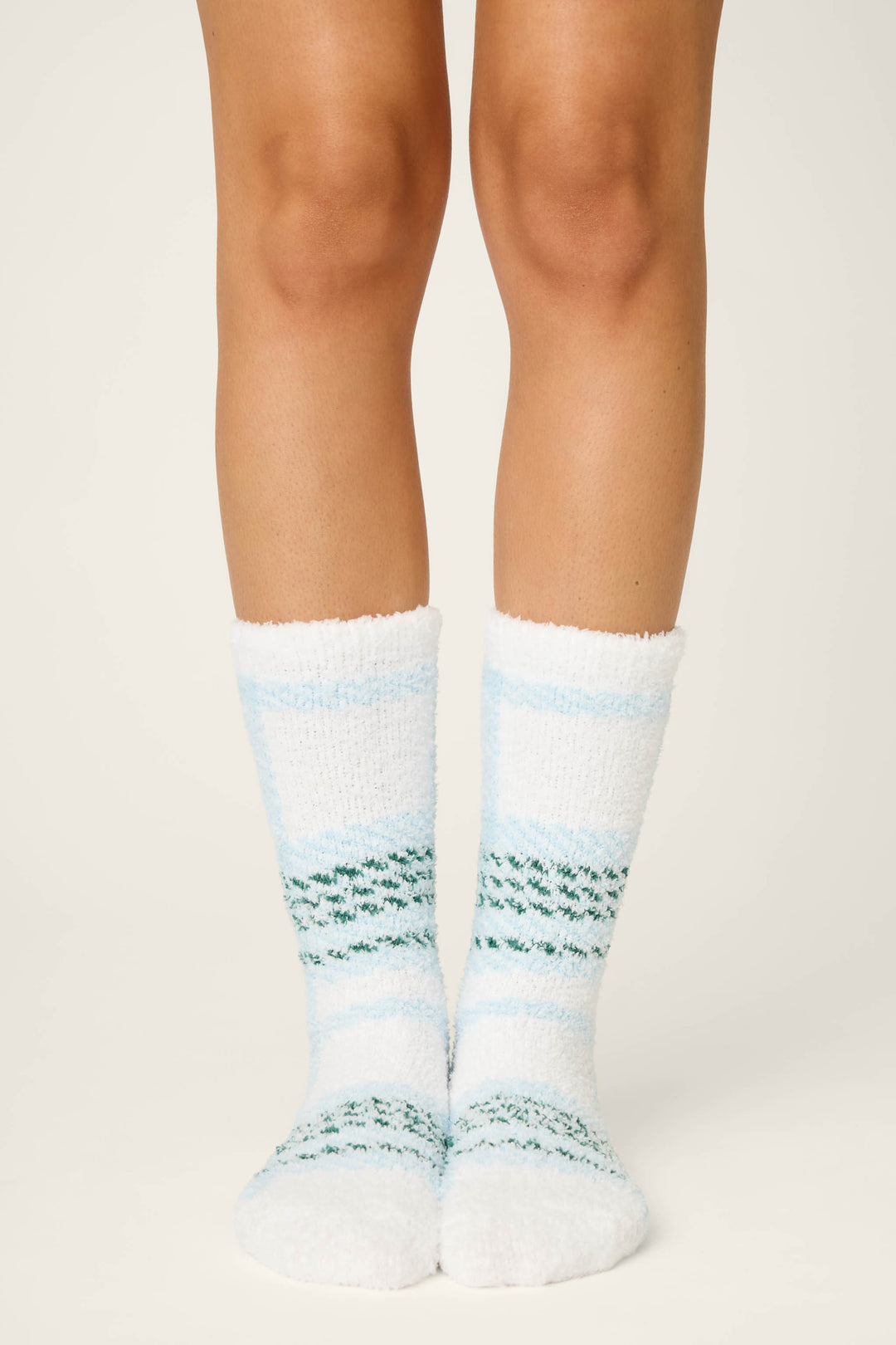 A person stands on a white surface wearing P.J. Salvage PLAID SOCKS WINTER WONDERLAND, shown from the knees down.