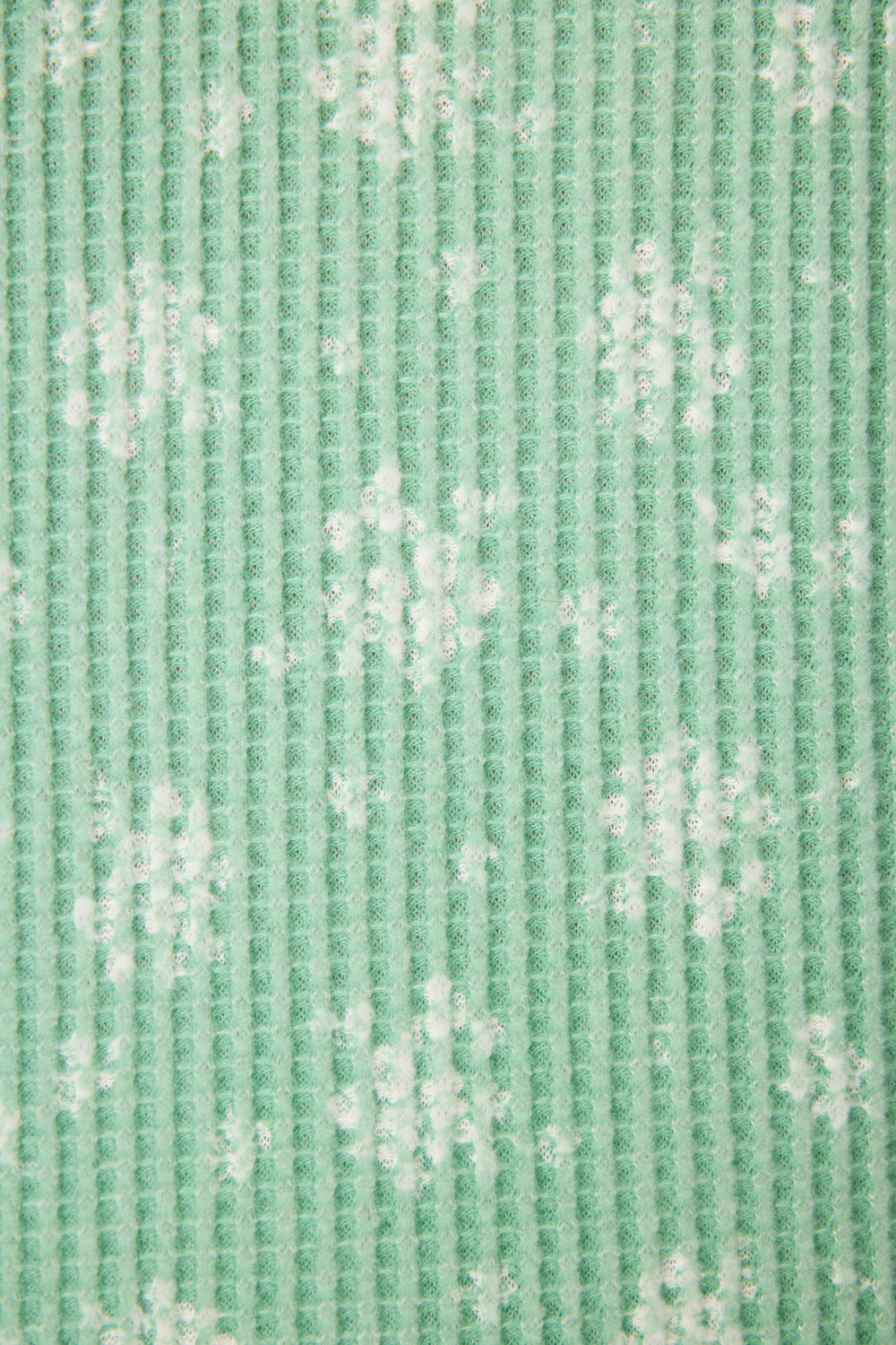 Close-up of the P.J. Salvage DTC Exclusive - SNOWFLAKE PJ SET 3 PIECE GIFT SET featuring textured green fabric with a vertical ribbed pattern and scattered white snowflake designs.