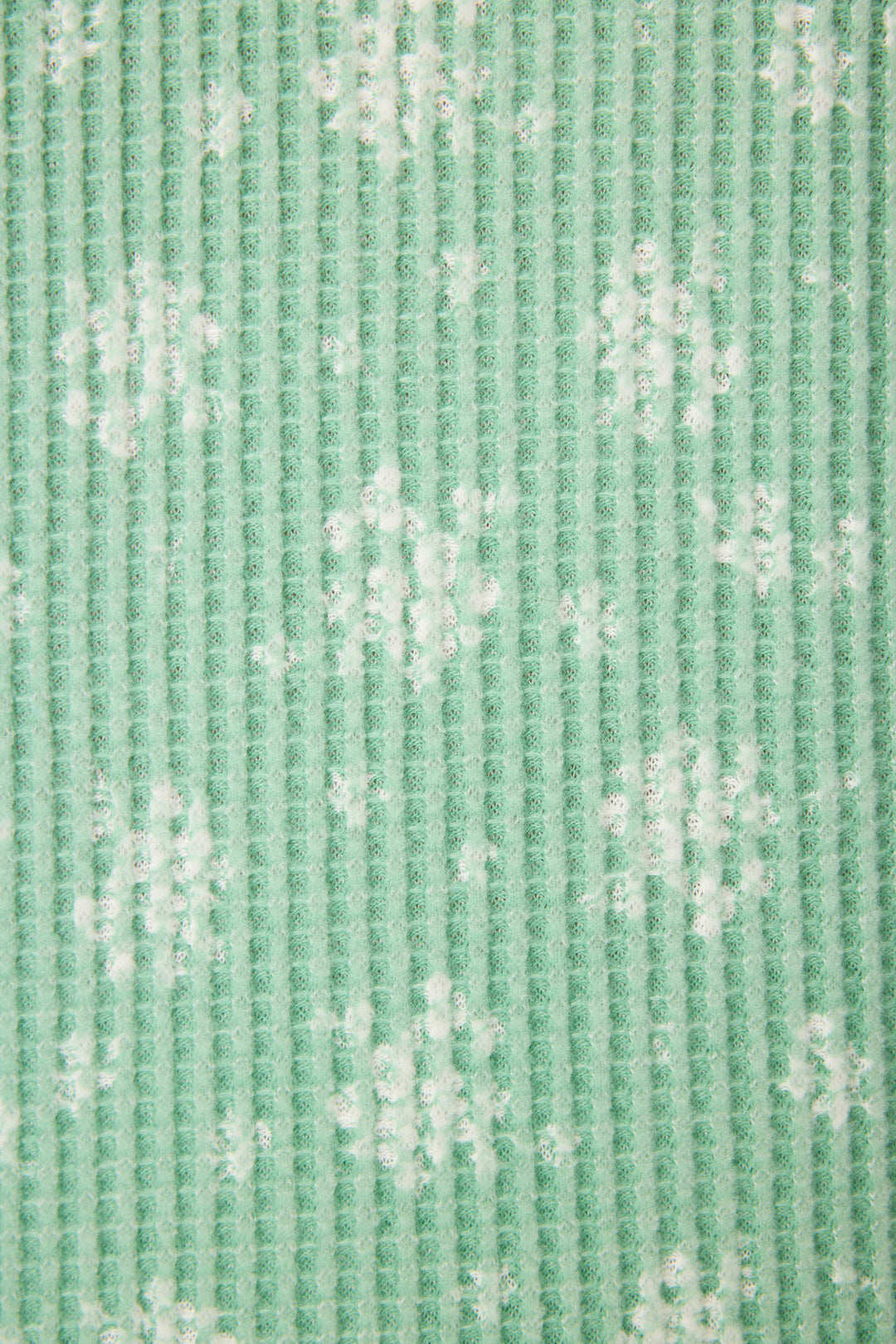 Close-up of the P.J. Salvage DTC Exclusive - SNOWFLAKE PJ SET 3 PIECE GIFT SET featuring textured green fabric with a vertical ribbed pattern and scattered white snowflake designs.