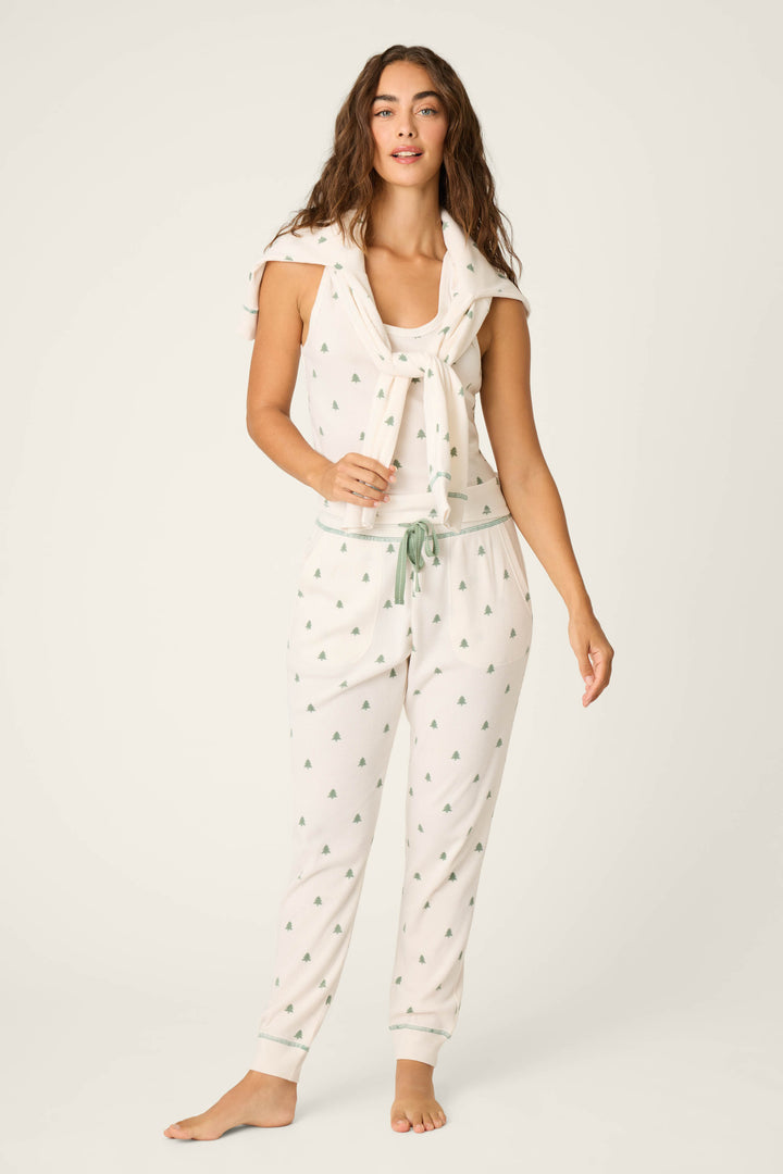 A person stands barefoot in the P.J. Salvage DTC Exclusive - PLAID PJ SET 4 PIECE GIFT SET, with a matching top tied around their shoulders and hands in the pants pockets, posed against a plain light background.