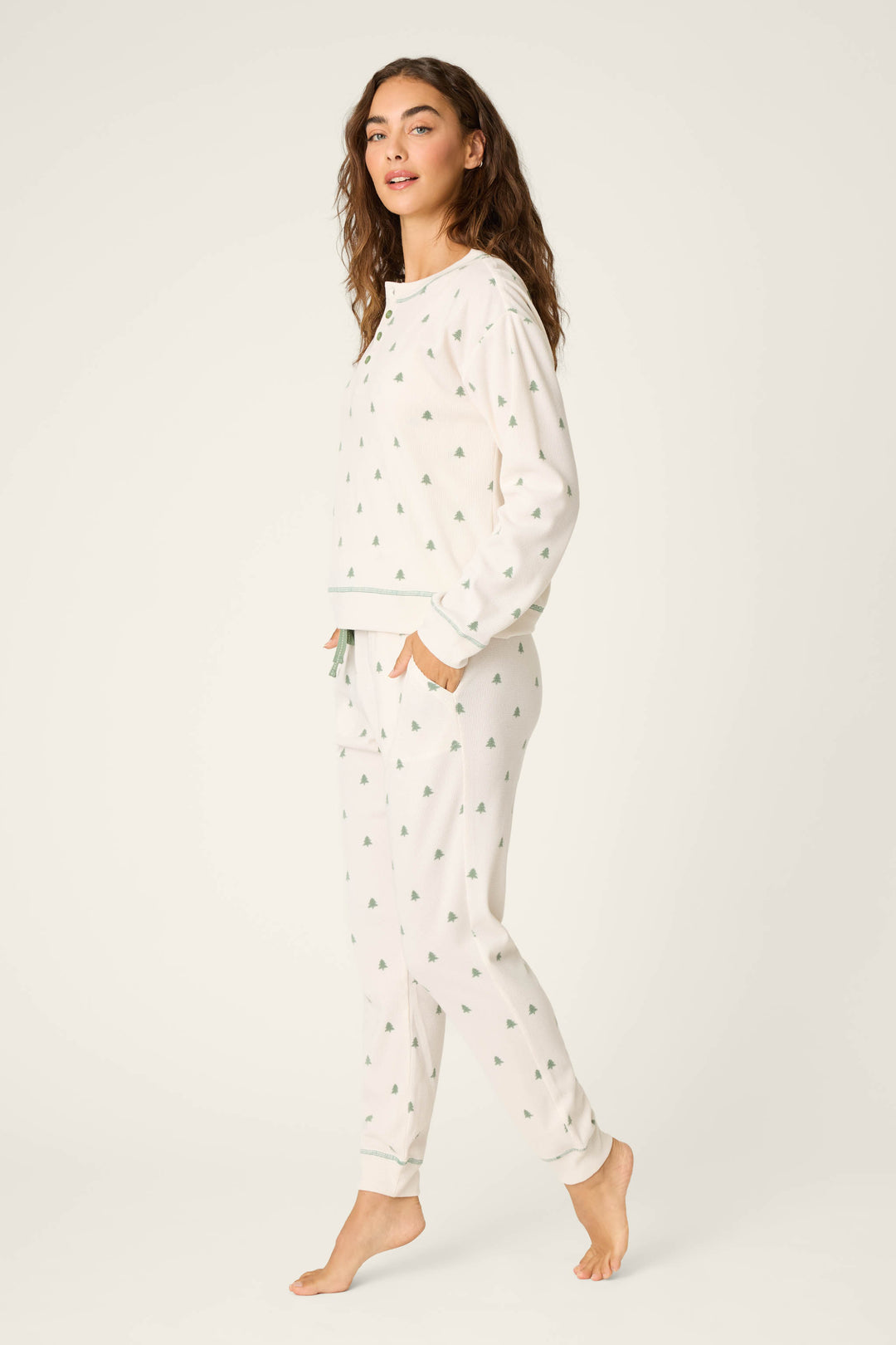 A woman stands barefoot against a plain background, wearing the P.J. Salvage DTC Exclusive - PLAID PJ SET 4 PIECE GIFT SET with her hands in her pockets, looking slightly past the camera.