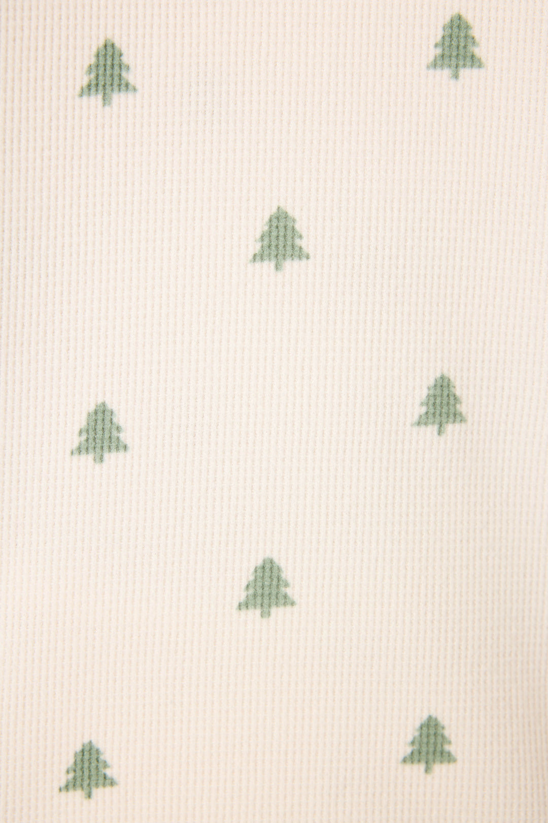 Close-up of the DTC Exclusive – PLAID PJ SET 4 PIECE GIFT SET by P.J. Salvage, showing light-colored, textured fabric with a repeating pattern of evenly spaced small green tree shapes.