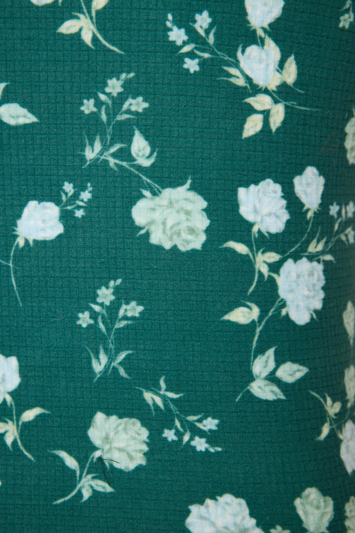 Close-up of the FLORAL RACERBACK TANK WINTER LAND by P.J. Salvage, featuring green textured fabric with a white and light yellow floral rose pattern scattered throughout.