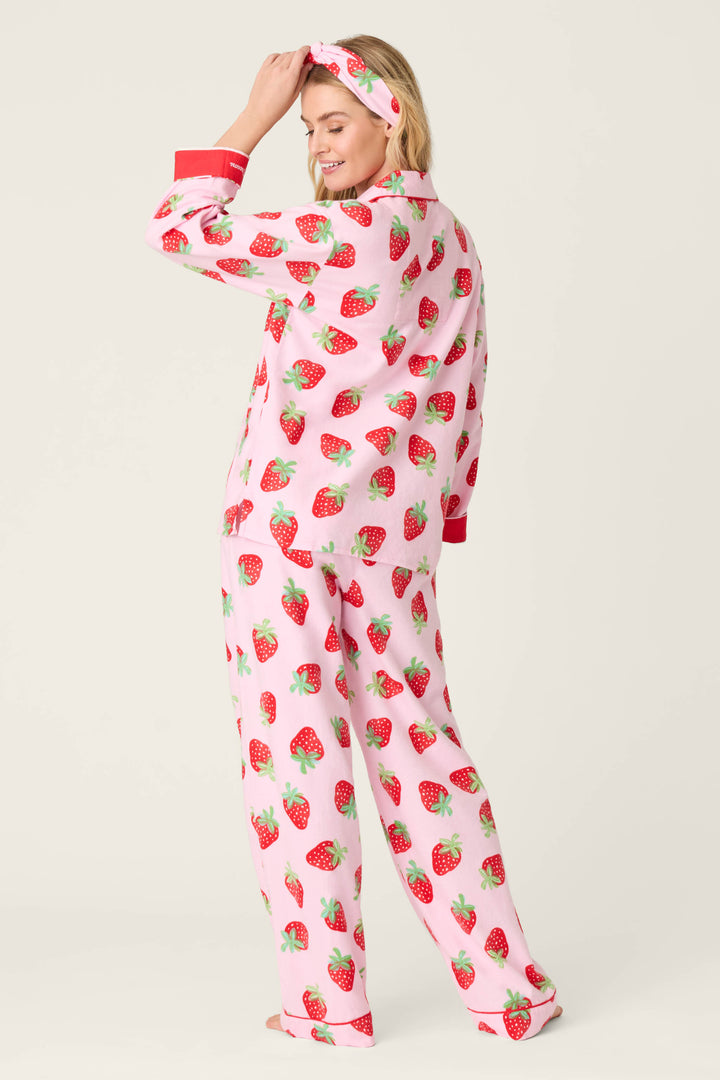 A person models the P.J. Salvage Sweet Dreams Strawberry Print 3-Piece Flannel PJ Set, turning slightly to the side and smiling while touching their matching headband.