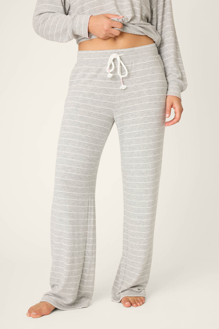 A person models P.J. Salvage's My Dog Is My Valentine Striped Open Leg Pants in light gray with a white drawstring, standing barefoot on a light background. The matching long-sleeve top is partially visible.