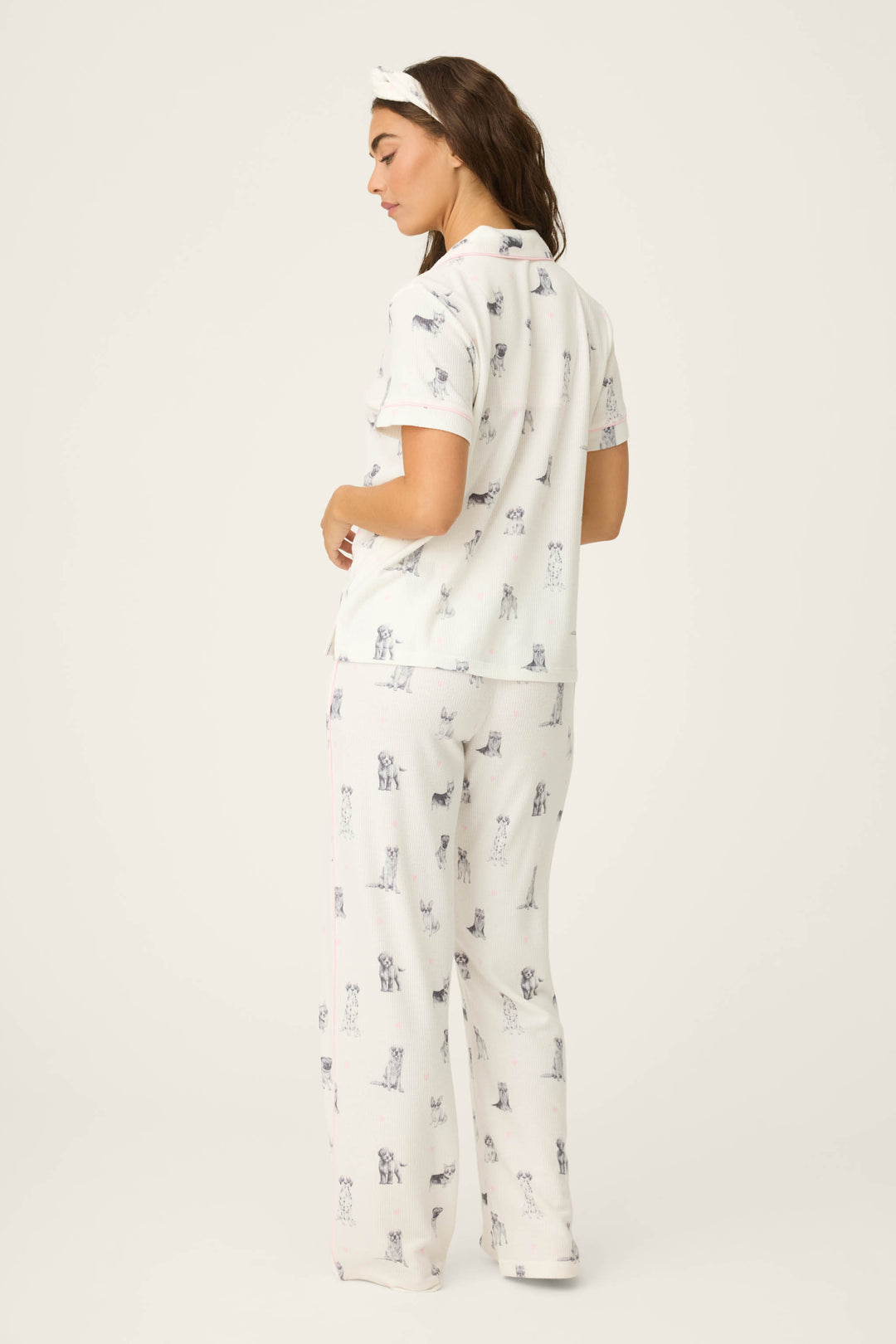A woman faces away, wearing the P.J. Salvage "My Dog Is My Valentine" 3-piece PJ set—white with a dog print and matching headband—against a plain, light background.