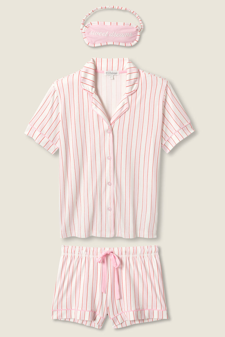 The P.J. Salvage Feeling Love Striped 3-Piece PJ Set features a pink and white striped short-sleeve button-up shirt, drawstring shorts, and a matching sleep mask embroidered with “sweet dreams.”.