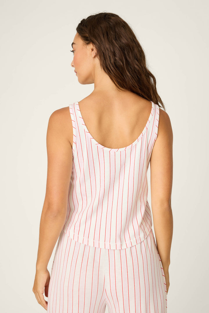 A woman with long brown hair is seen from the back wearing the P.J. Salvage Feeling Loved Striped Tank Top and matching pants—both relaxed fit, white with vertical red stripes—standing against a plain light background.