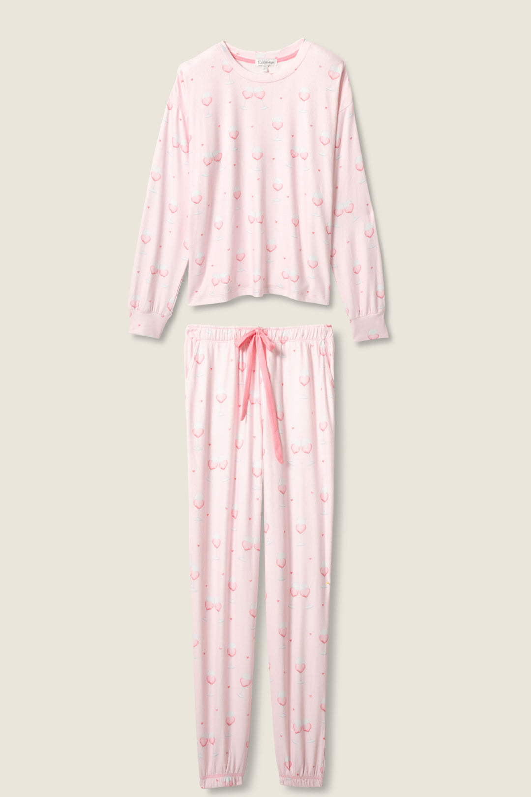 The Happy Hour Wine Glass Print PJ Set by P.J. Salvage is a two-piece pajama set with a long-sleeve top and pants, featuring a playful wine glass print. The pants have an elastic waistband and pink drawstring for added comfort.