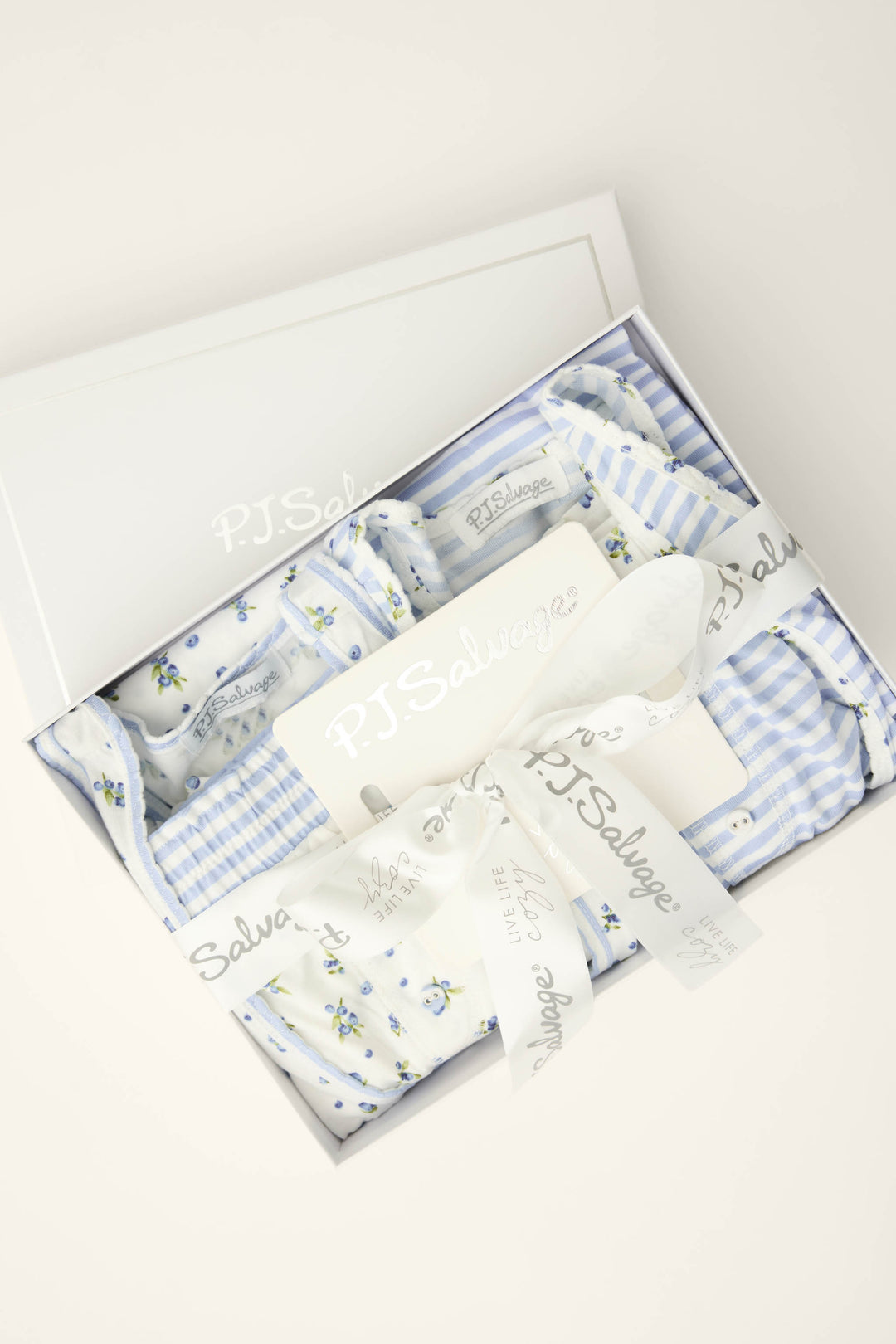 The Mix and Match Blueberry Dreams Sleep Set by P.J. Salvage features blue and white floral and striped sleepwear, elegantly boxed with branded ribbon and packaging, shown from above on a light background.